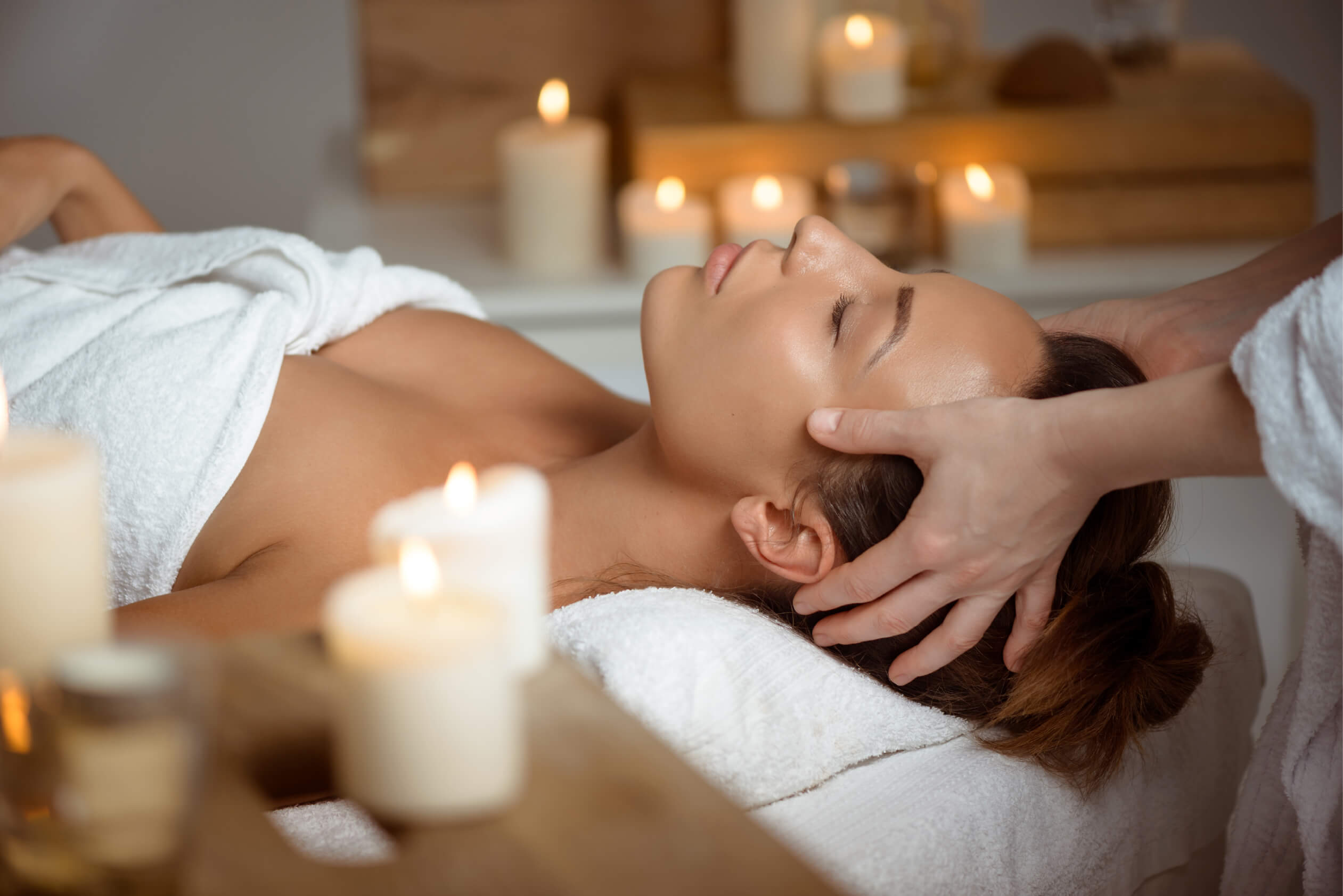 Young woman having face massage relaxing spa salon